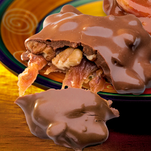 Close-up of Lammes Candies Pecan Chocolate Caramel Longhorns Candies with a broken piece revealing gooey caramel, crunchy pecans, and a thick milk chocolate coating.