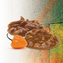 Two Lammes Candies Habanero Pralines beside an orange habanero pepper on a textured background.