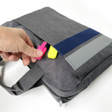 A grey satchel with a zippered pocket, featuring blue and grey stripes and brightly coloured tags.