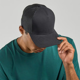 A black trucker cap with a mesh back, worn by a person in a teal shirt. The cap features a logo on the front.