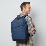 A blue backpack with black accents, worn on a man's back, featuring a logo on the front.