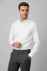A white long sleeve button-up shirt with a pocket, paired with grey trousers. The shirt features a logo.