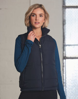A navy heavy quilted vest with a high collar, featuring a zip closure, worn over a blue long-sleeve top.