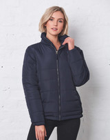 A navy heavy quilted puffer jacket with a zip and high collar, featuring a woman posing against a white brick wall.