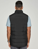 A black insulated puffer vest with a 3D cut, viewed from the back, worn over a light blue shirt.