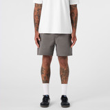 A pair of grey dress shorts featuring a simple design and a logo, modelled by a person with tattoos.