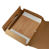A cardboard gift box containing a bamboo notebook and a pen, all in natural tones.