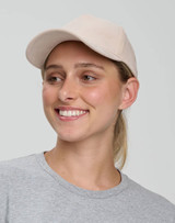 A beige Jacquard Texture 5 Panel Cap worn by a smiling individual, featuring a logo on the front.