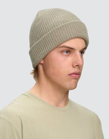 A beige cable knit snug beanie displayed on a model, featuring a ribbed design and a logo.