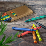 A crayon set featuring six vibrant colours in a cardboard box, with some crayons scattered on a wooden surface.