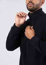 A black polar fleece half zip top with a high collar and a zipper, featuring a person adjusting the zip.