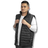 A black puffer vest is worn by a model, featuring a high collar and zip closure, set against a white background.