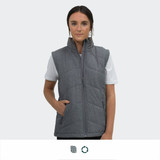 A woman wears a grey puffer vest with a high collar and side pockets. The vest has a logo.