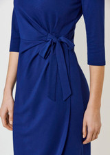 A blue dress featuring a tied detail at the waist and three-quarter sleeves. The dress has a smooth, elegant look.