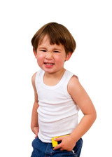 A child wearing a white singlet and blue jeans, smiling with a playful expression, holding something yellow in their pocket. A child wearing a white singlet and blue jeans, smiling with a playful expression, holding something yellow in their pocket.