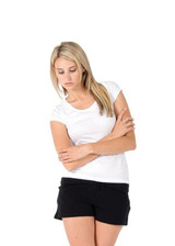 A women's white jersey scoop neck T-shirt, worn with black shorts, featuring a logo. The model has long blonde hair.