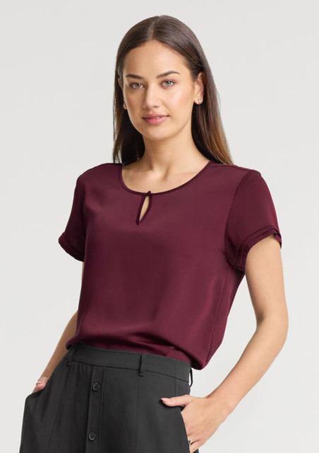 A maroon women's short sleeve blouse with a keyhole detail at the neckline, paired with black trousers.