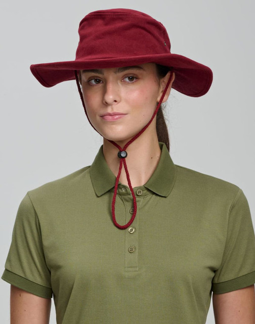 A beige bucket hat with a chin strap and a branded logo, featuring a wide brim for sun protection.