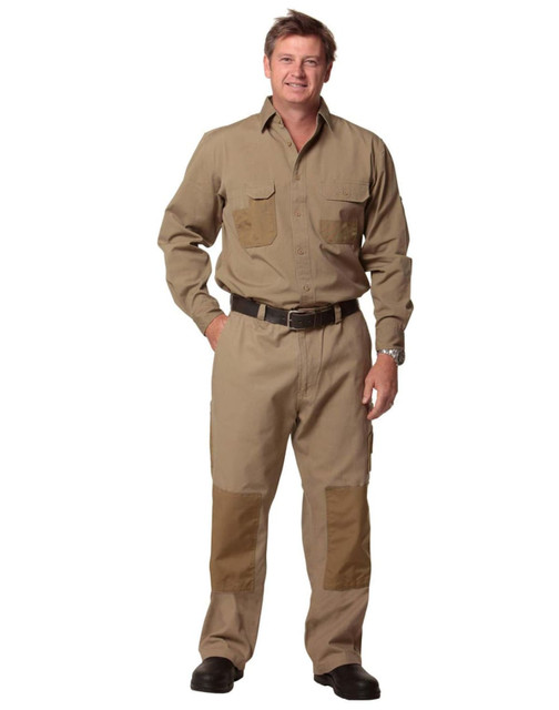 A man stands wearing khaki work pants with reinforced patches, accompanied by a matching shirt and belt, featuring a branding logo.