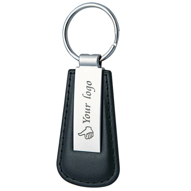 A keyring featuring a black leather holder and a metallic tag, with a logo on the tag.