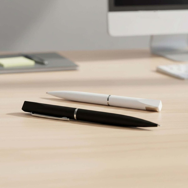 A black pen and a white pen laid on a wooden desk, with a computer in the background. The pens have sleek designs.