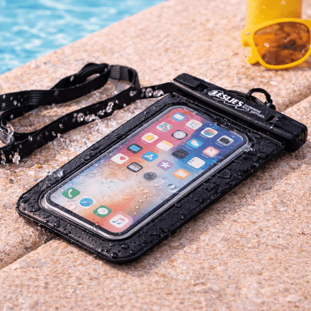 A waterproof phone pouch in black, featuring a clear front, resting on a poolside with water droplets and sunglasses nearby.