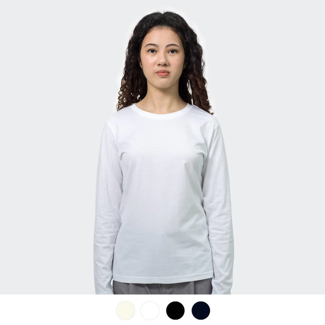 A woman wearing a long sleeve crew shirt in white, featuring a subtle logo. Available in additional colours below.