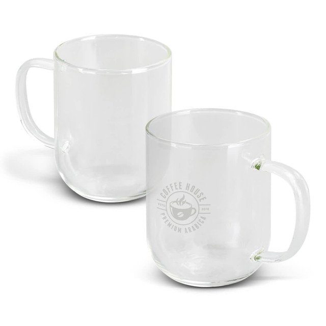 A glass mug in clear colour with a handle and a logo on one side. Two mugs are displayed. A glass mug in clear colour with a handle and a logo on one side. Two mugs are displayed.