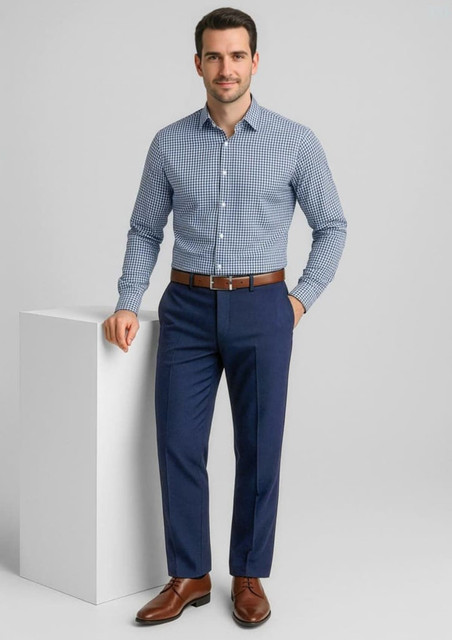 A man in a checkered shirt and brown belt poses in navy slacks, showcasing a sophisticated look.