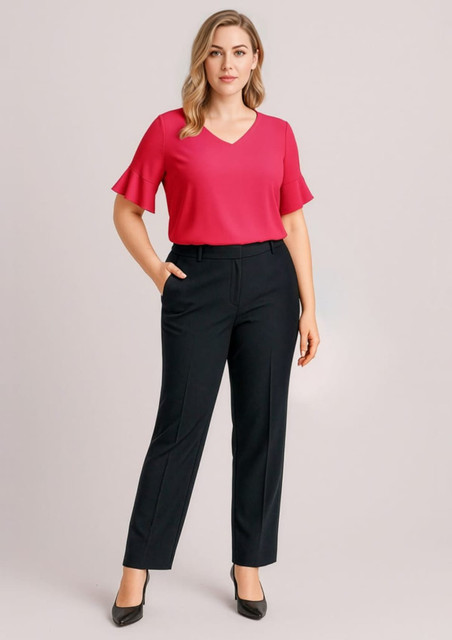 A woman wearing a pink top and black adjustable waist pants stands with one hand in her pocket. The pants have a sleek design.