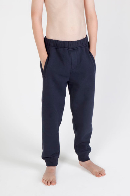 Junior track pants in navy, featuring an elastic waistband and side pockets, displayed on a bare torso.