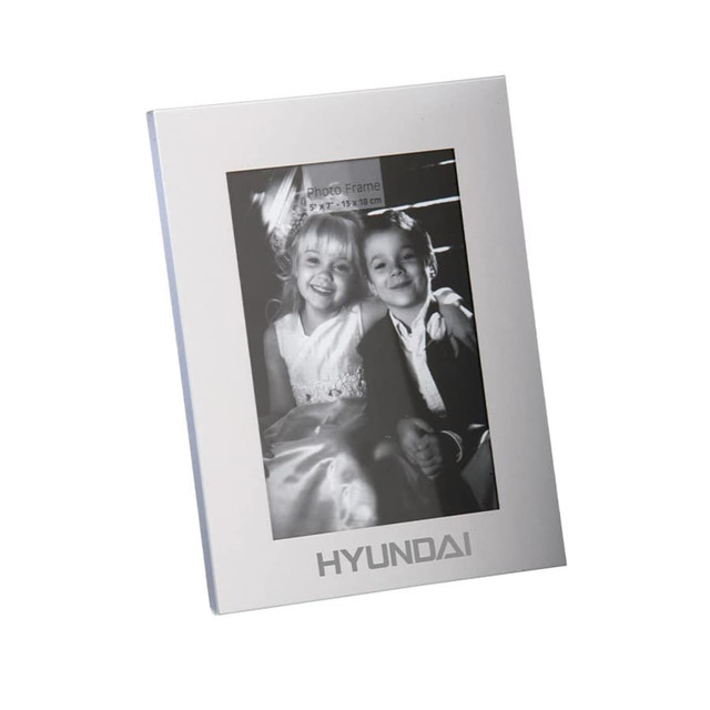 A classic aluminium photo frame in silver, featuring a black and white photo of two children. Includes a logo.