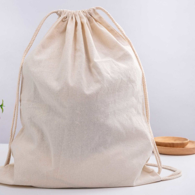 A beige drawstring bag with a cinched top, featuring sturdy drawstrings. It has a simple and versatile design.