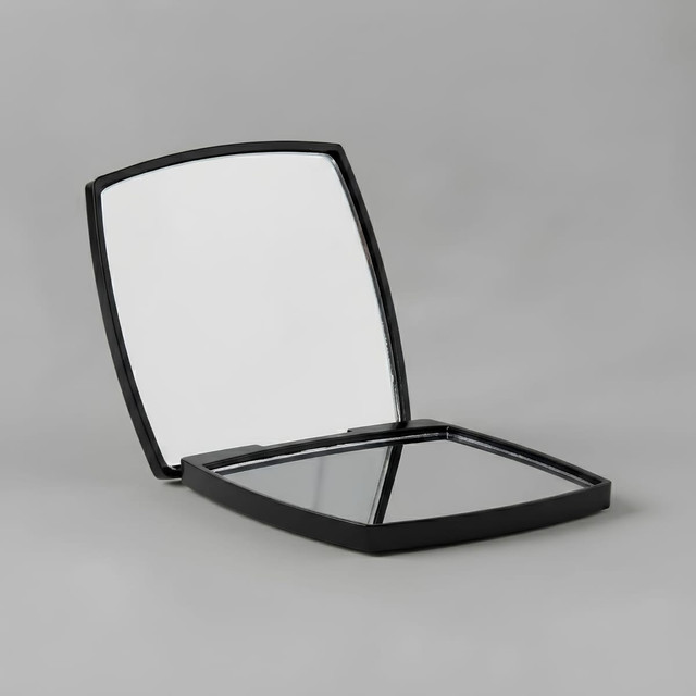 A compact mirror with a sleek black exterior, featuring two reflective surfaces inside. It has branding visible.