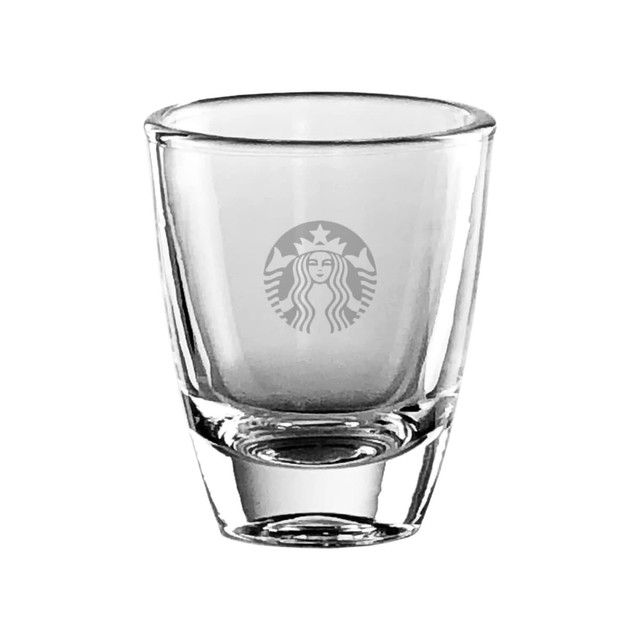 A transparent shot glass with a rounded base, featuring a logo. It's designed for various beverages.