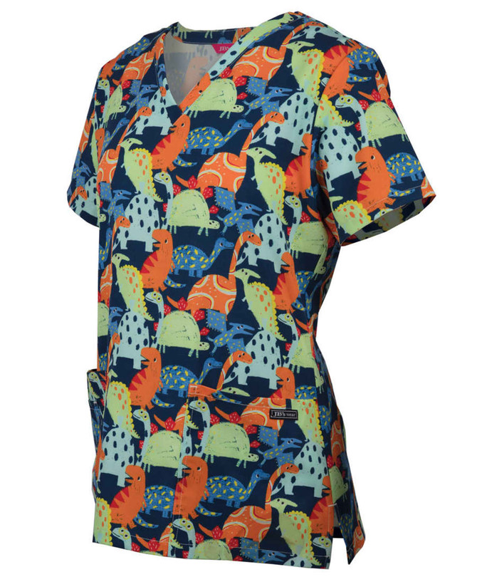 A scrub top featuring a vibrant dinosaur print in green, orange, and blue hues with a pocket. It has a logo.