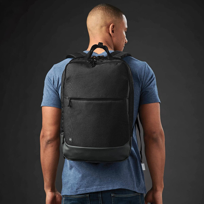 A black laptop backpack is worn on a person's back, featuring a sleek design and a matte finish.