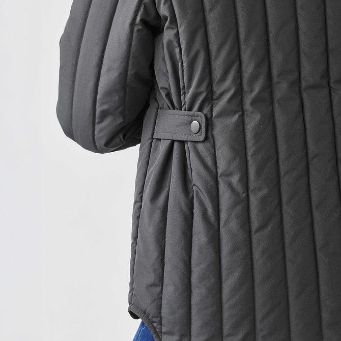 A thermal jacket in dark grey with quilted texture and button detail on the sleeve. It features a relaxed fit.