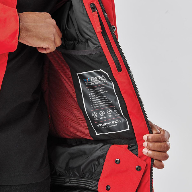 A red Men's Denali Parka featuring a zippered pocket and a branded label inside the jacket.