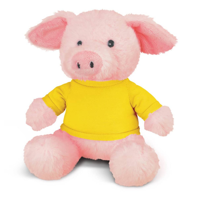 A pink plush pig toy wearing a yellow shirt, featuring large ears and a cute face. It has a logo on the shirt.