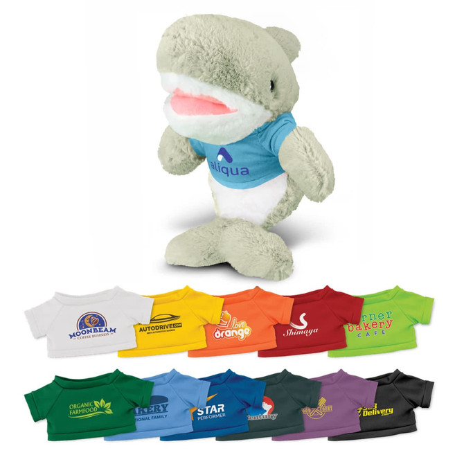 A plush shark toy in grey with a blue shirt, surrounded by various brightly coloured T-shirt designs in different hues.