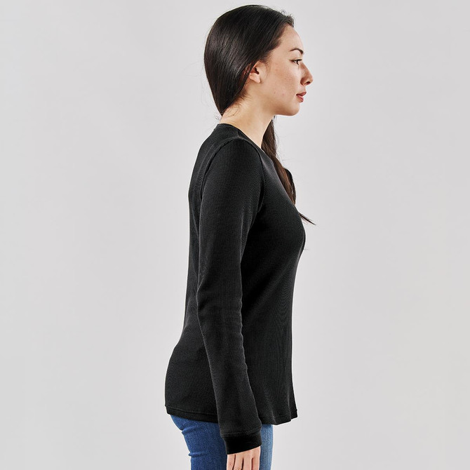 A woman is wearing a black Ashburn crew neck shirt, viewed from the side, with long sleeves and a fitted silhouette.