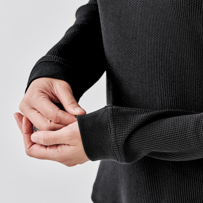 A black crew neck shirt with textured fabric, featuring fitted sleeves and a snug fit around the wrists.