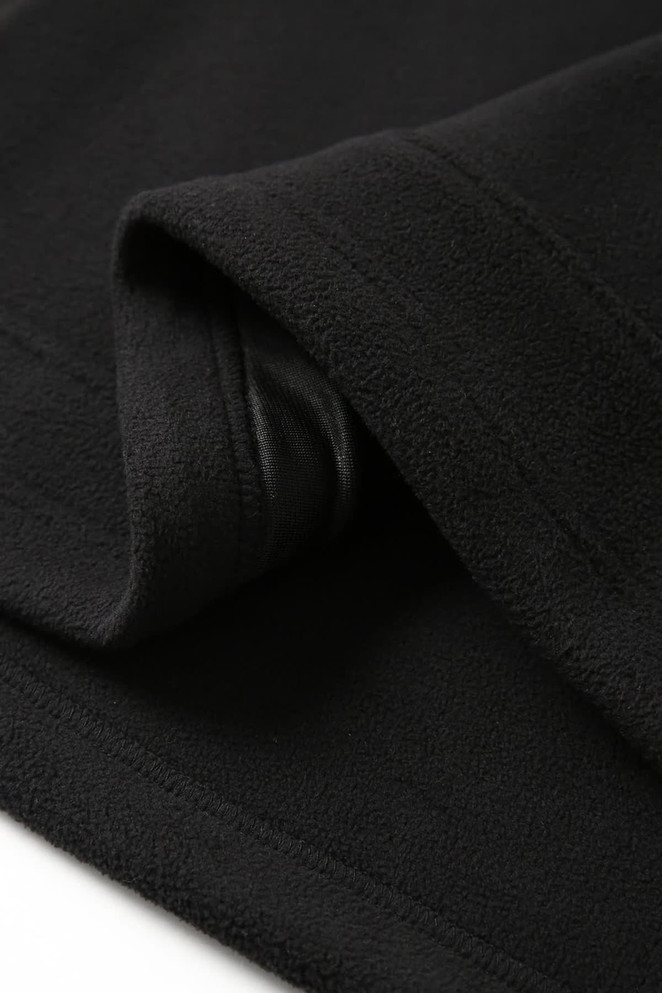 A black polar fleece half zip top featuring a soft, textured fabric and a folded collar. It has a logo.