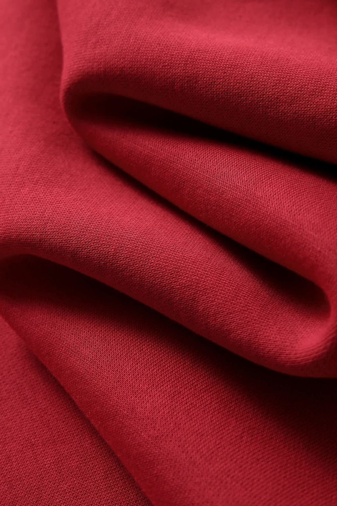 A red fleece fabric showcasing soft, textured folds, suitable for jumpers. Features a logo present on the fabric.