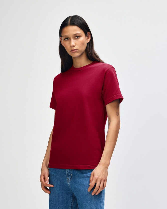 A heavyweight unisex t-shirt in burgundy, featuring a simple design and short sleeves, paired with blue jeans.