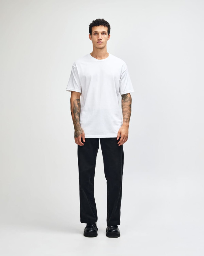 A lightweight white unisex T-shirt displayed on a model wearing baggy blue jeans and black sneakers, featuring a logo.