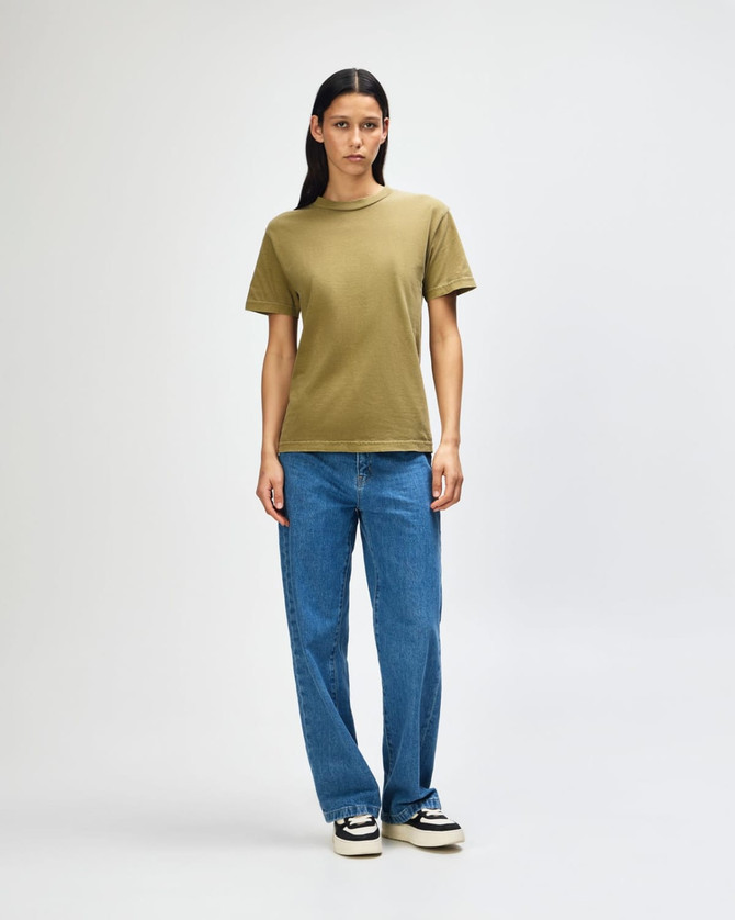 A unisex heavyweight cotton T-shirt in olive green, paired with light blue cargo pants. A logo is present.