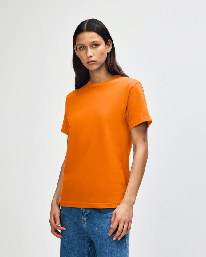 An orange heavyweight cotton unisex T-shirt on a model, paired with light blue jeans.