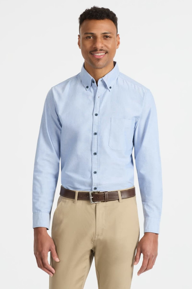 A light blue men's long sleeve button-up shirt with a pocket and a logo on the chest, paired with beige trousers.